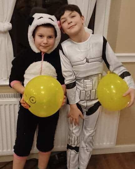 Dwóch chłopców w strojach karnawałowych trzyma żółte balony
