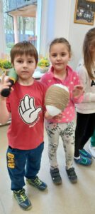 chłopiec i dziewczynka pokazuja wielkie jajo owiniete sznurkiem