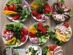 widok z góry na plat kuchenny, na nim talerze z pokrojonymi warzywami ( papryka, sałata, ogórki, rzodkiewki, szczypiorek)