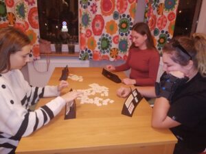Trzy osoby grają w grę, której elementy leżą na stole
