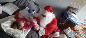 Dziecko w pozycji leżącej na swoim łóżku ma spotkanie z Mikołajem